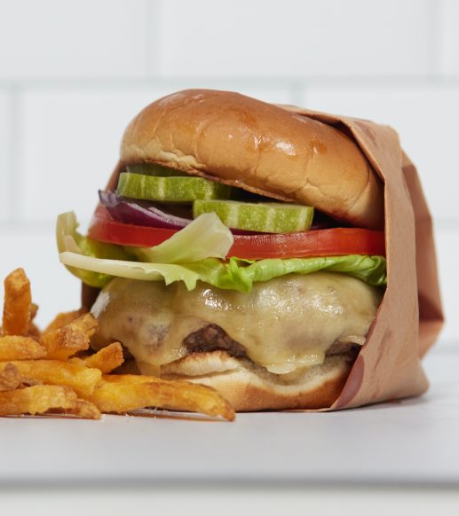 cheeseburger in wrapper next to french fries